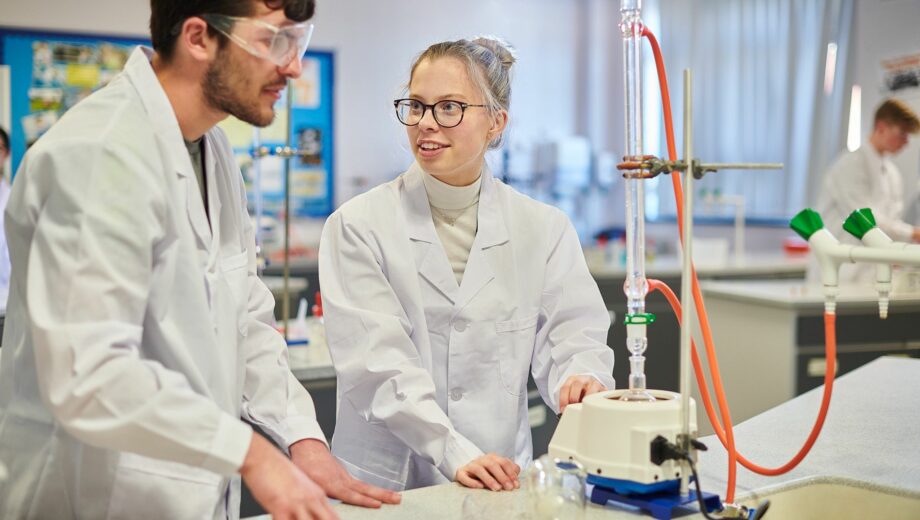 Boy and girl in a Science lab wearing lab coats doing an experiment.